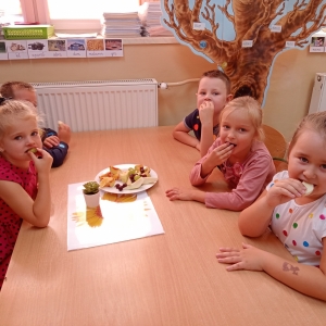 Kilkoro dzieci siedzi przy stoliku i je owoce