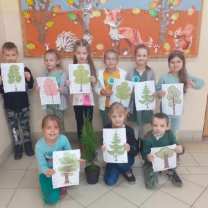 Uczniowie w klasie prezentują wykonane przez siebie prace przedstawiające drzewa.
