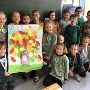 Uczniowie w klasie prezentują plakat przedstawiający drzewo.