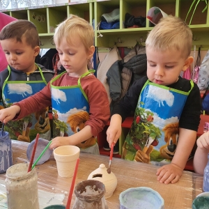 Dzieci malują gliniane naczynia. 