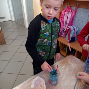 Dzieci malują specjalnymi farbami gliniane naczynia.