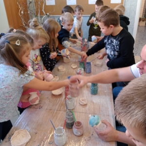 Dzieci malują specjalnymi farbami gliniane naczynia.