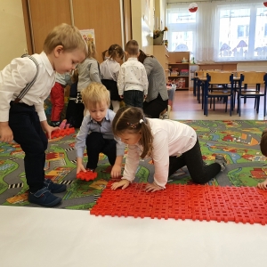 Dzieci układają z klocków flagę Polski. 
