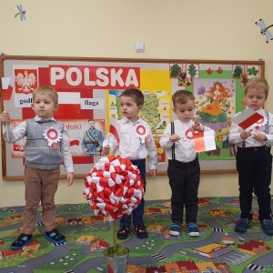 Dzieci trzymają w rączkach flagę Polski.