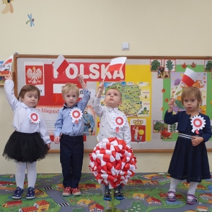 Dzieci trzymają w rączkach flagę Polski.