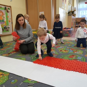 Dzieci układają z klocków flagę Polski. 