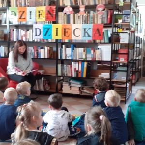 Zaciekawione dzieci słuchają bajki czytanej przez panią bibliotekarkę