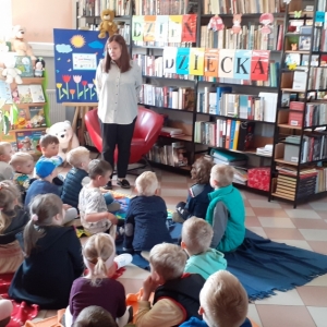 Zaciekawione dzieci słuchają bajki czytanej przez panią bibliotekarkę