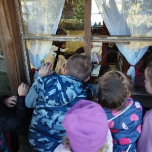 Uczniowie zaglądają przez okno do chatki